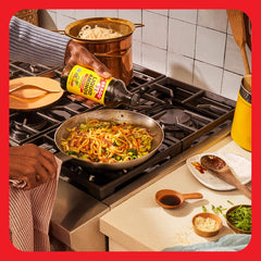 Bragg pouring liquid aminos into pan, illustrating easy seasoning control