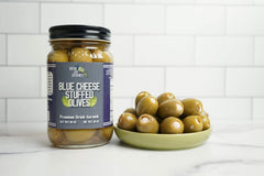 Green Jay Gourmet olives on a cheese board providing savory contrast and visual appeal