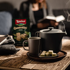 Hand holds Loacker Quadratini matcha wafer to show bite-size scale and portion convenience