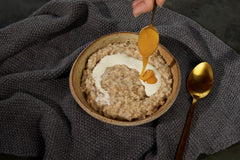 Manuka Health honey dripping from a wooden spoon illustrating creamy texture benefit