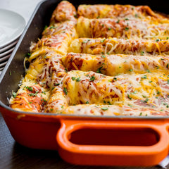 Sauce made from McCormick mix being poured into baking pan, ensures evenly seasoned enchiladas