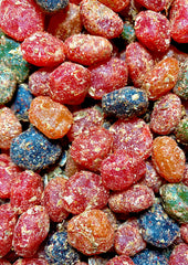 Noms pouch open on a beach towel with gummies, illustrating portable Hawaiian snack enjoyment