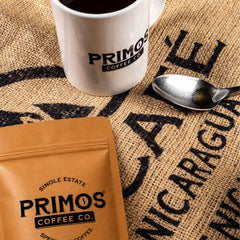 Primos Coffee Co. scoop with coarse grounds beside scale showing correct portioning benefit