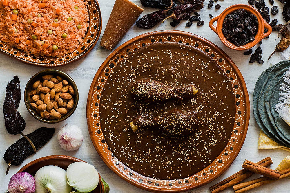 Amazing Chiles & Spices powder being stirred into mole sauce, adding rich color and depth