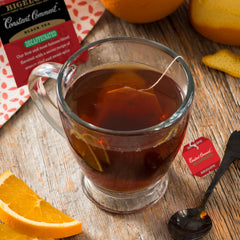 Bigelow Constant Comment individually foil-wrapped tea bag held between fingers demonstrating freshness