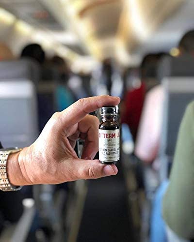 Bittermilk vial in hand next to a coin to show compact single-serve scale