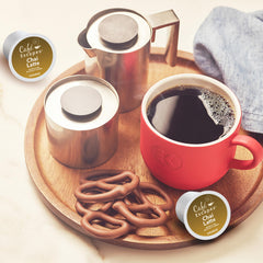 Café Escapes pod held in hand illustrating single-serve scale and portability benefit