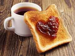 Cane River Mayhaw Jelly spread on warm biscuit illustrating tasty breakfast enhancement