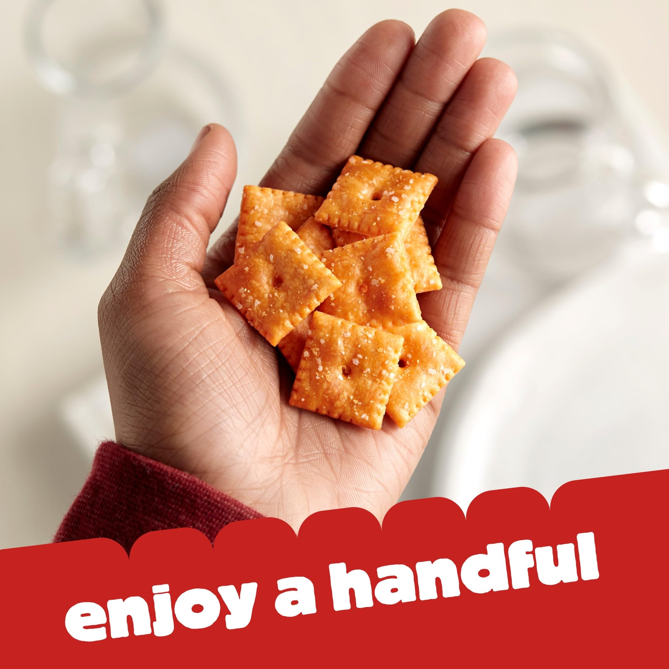 Hand holding a Cheez-It cracker ready to eat with portability benefit