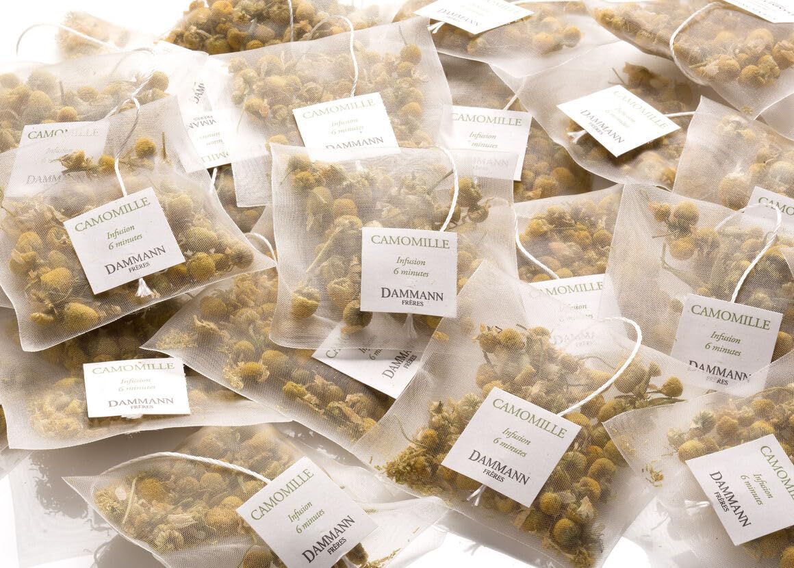 Dammann Freres Cristal sachet close-up revealing whole chamomile flowers and clear infusion