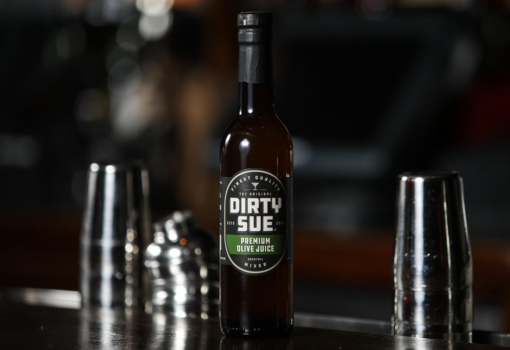Dirty Sue being poured into a cocktail adding balanced briny lift