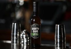 Dirty Sue being poured into a cocktail adding balanced briny lift