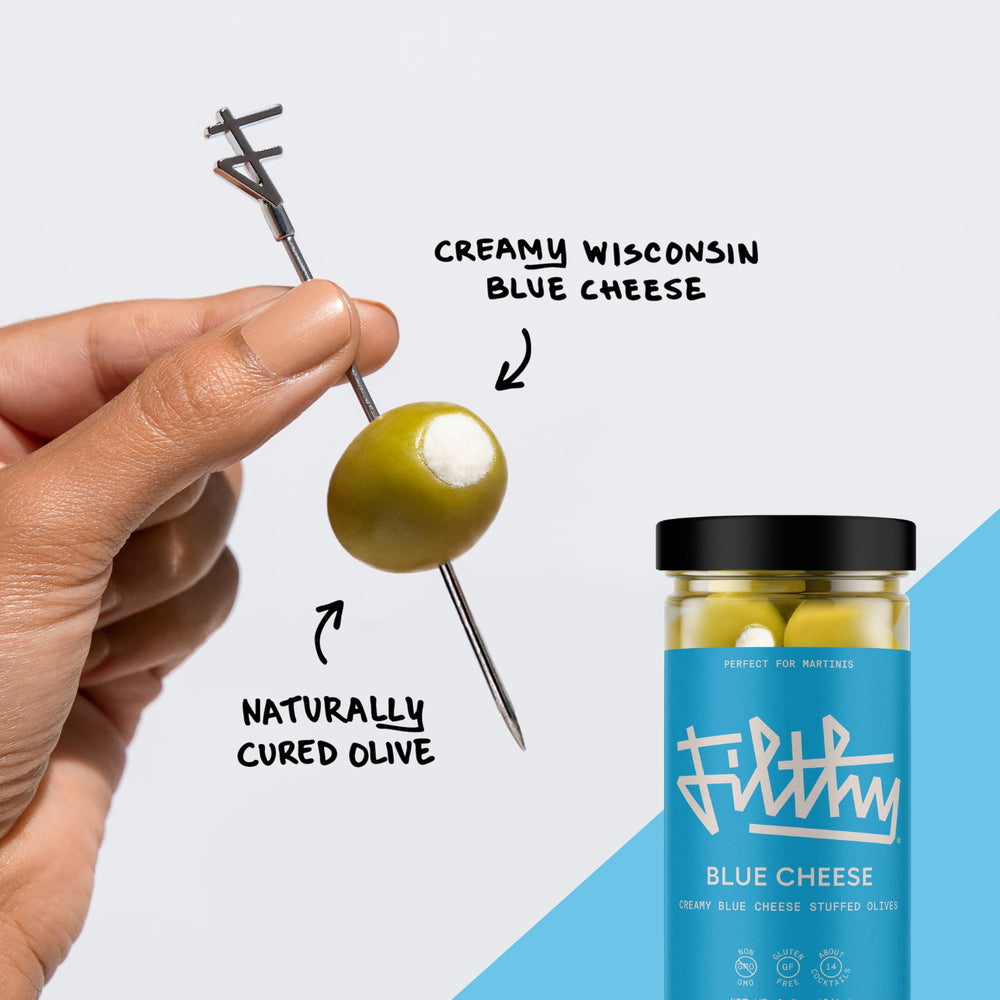 Filthy olive skewered in martini glass, adds savory cocktail garnish appeal