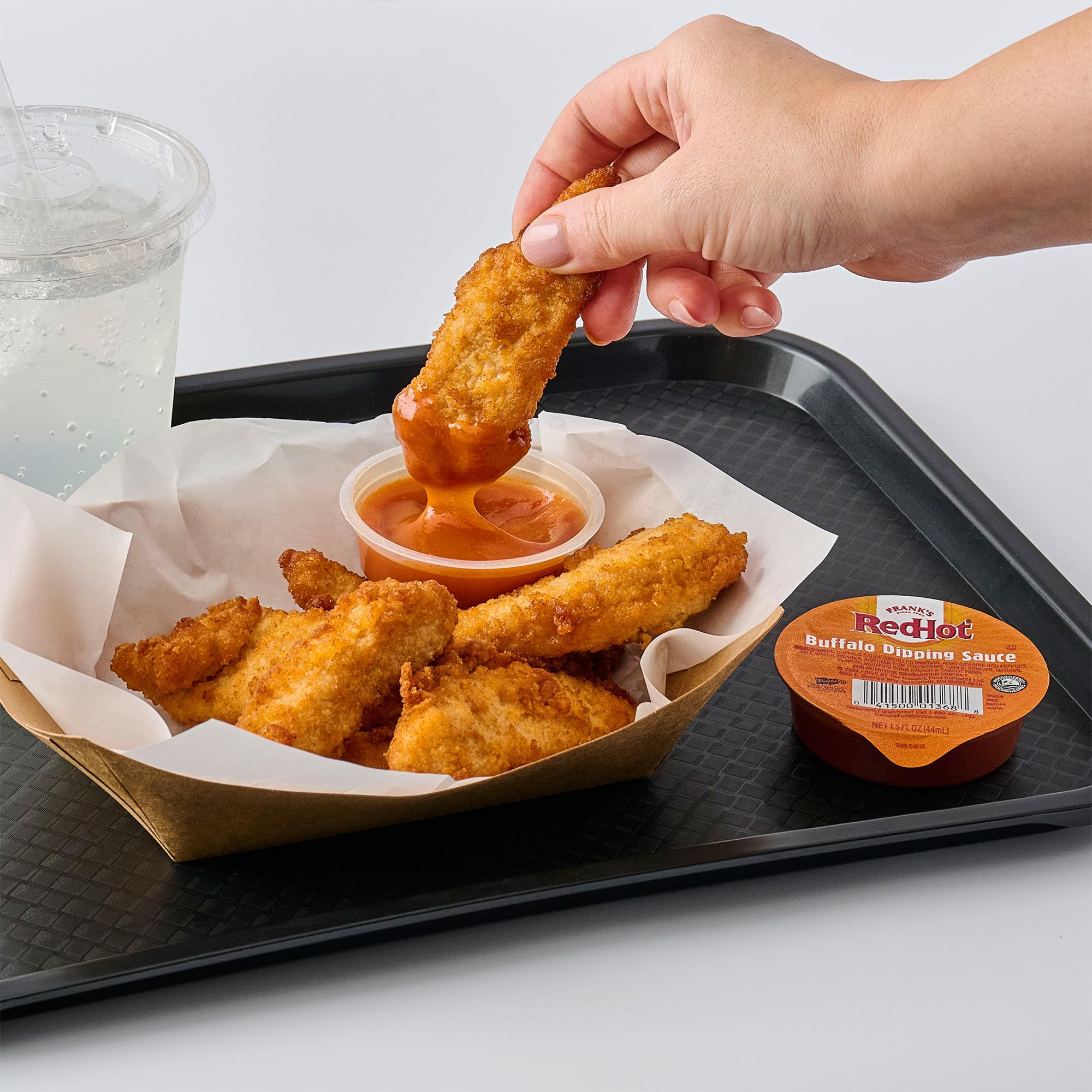 Frank's RedHot pouring from open cup onto wing showing convenient use