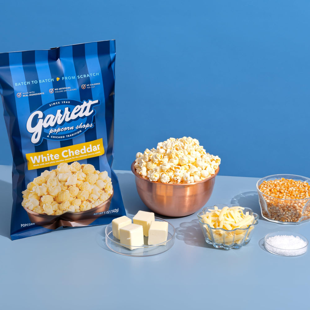 Four Garrett Popcorn white cheddar bags lined up to display the pack quantity and easy storage option