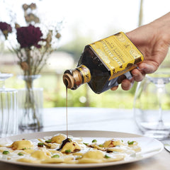 Giusti pouring thick balsamic onto spoon demonstrating rich viscosity benefit