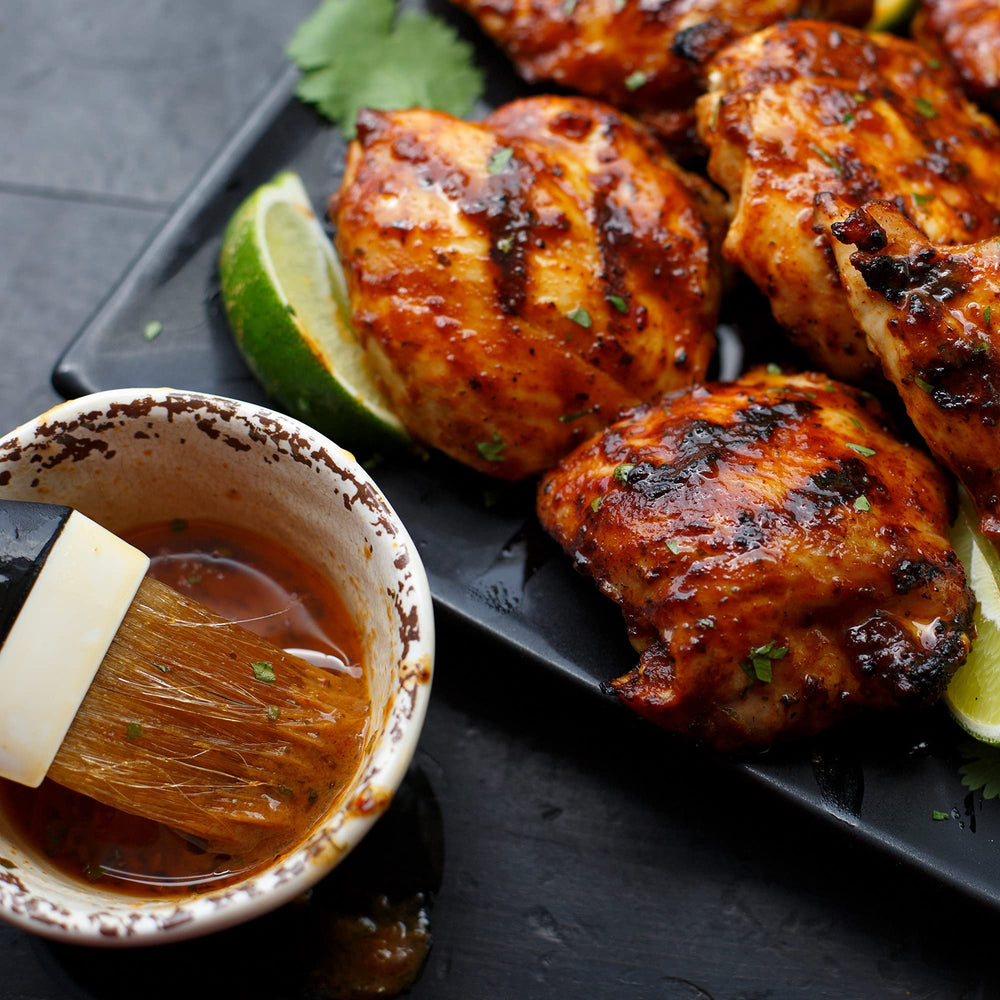 Grill Mates chicken grilling over flames with smoky mesquite finish