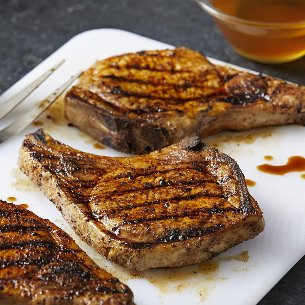 Pork chops on grill being basted with Grill Mates marinade for added flavor