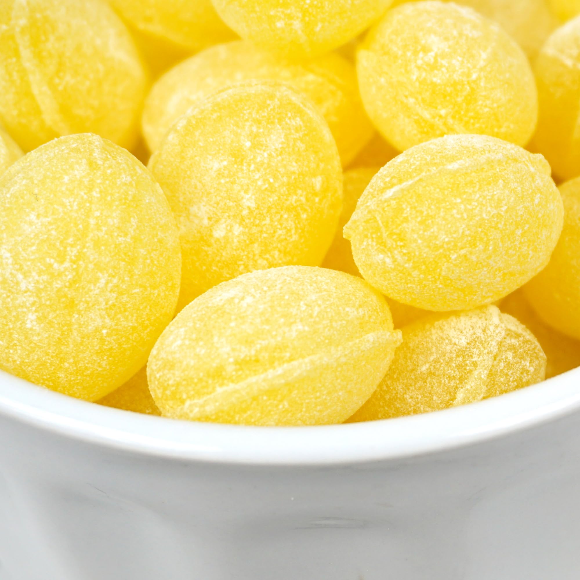 Hand holding one Claeys lemon drop from The Hampton Popcorn Company showing size and shape
