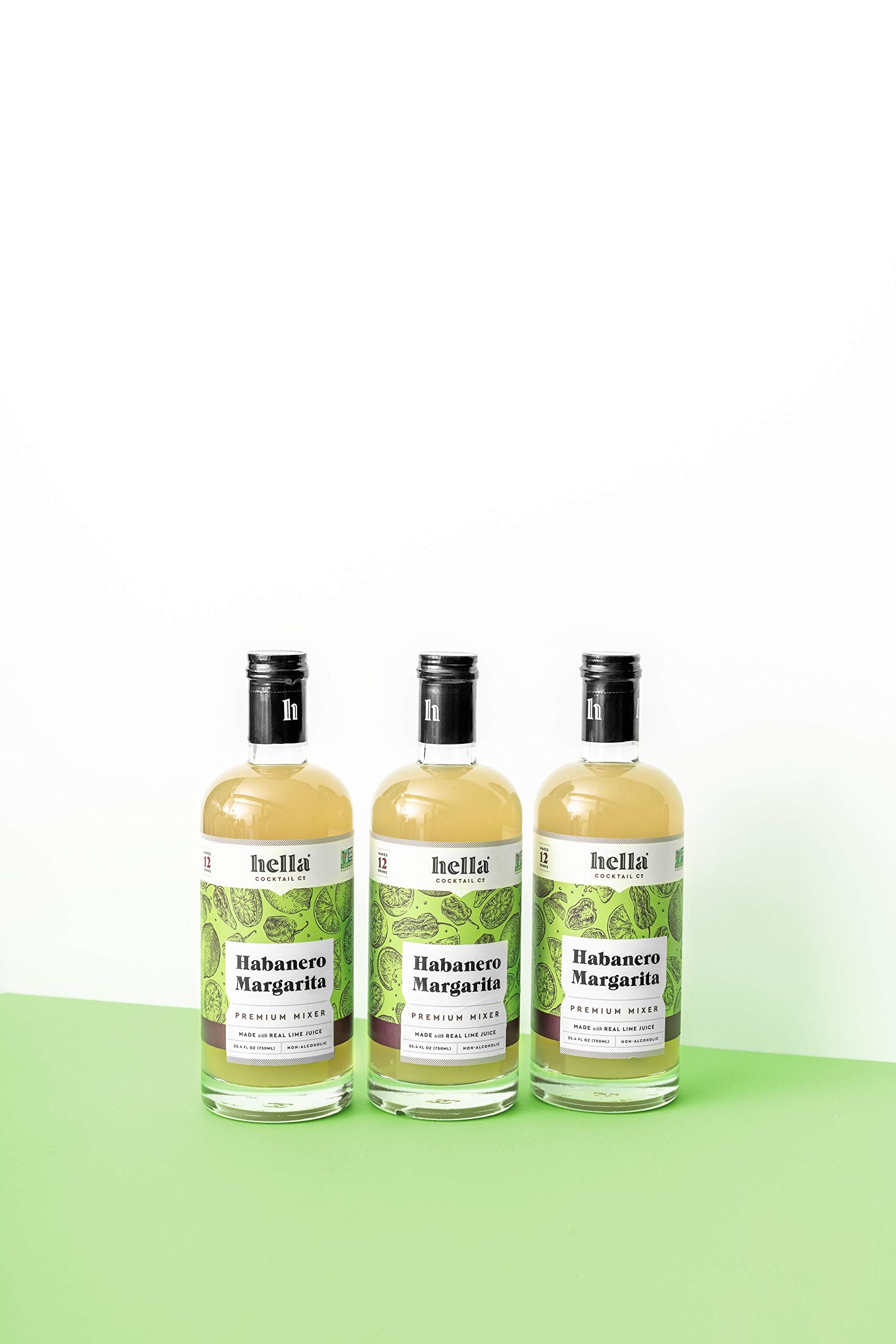 Hella Cocktail Co. limes and habanero peppers beside bottle highlighting natural ingredients