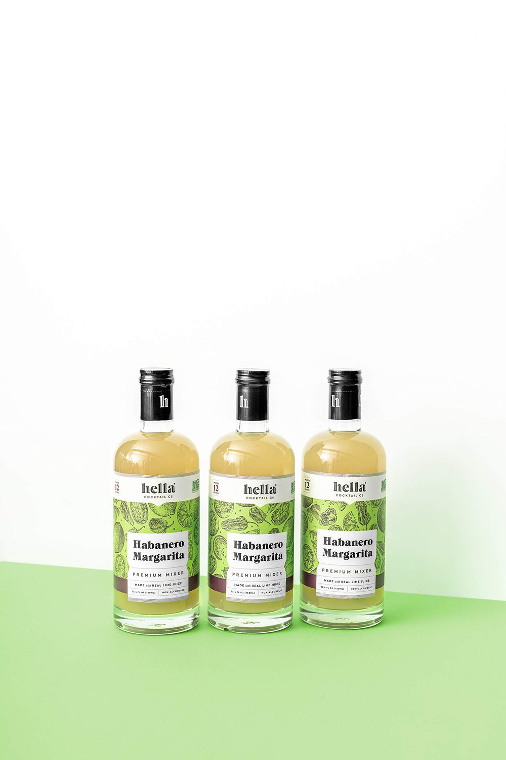 Hella Cocktail Co. limes and habanero peppers beside bottle highlighting natural ingredients