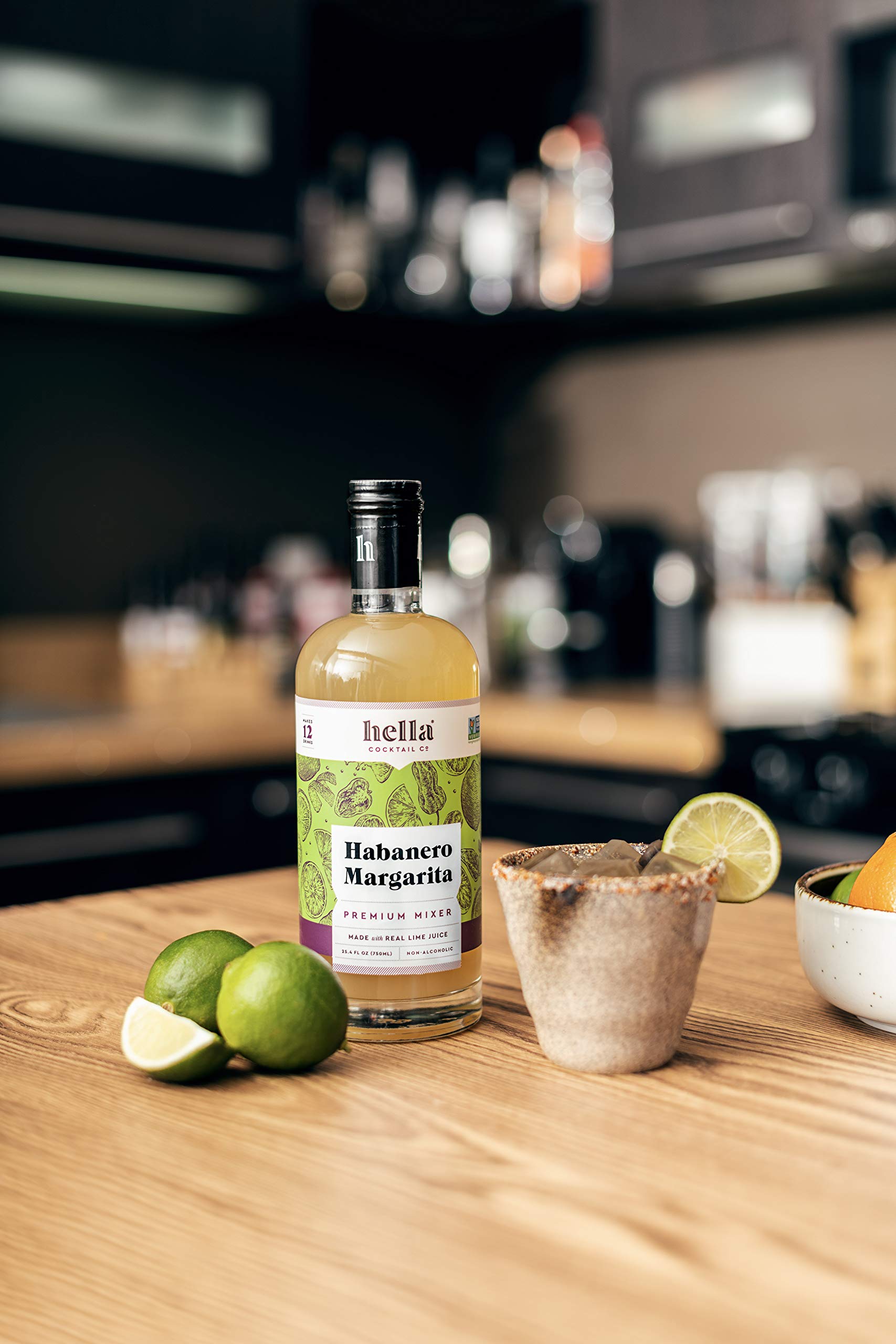 Hella Cocktail Co. bottle next to lime for scale showing real-juice authenticity