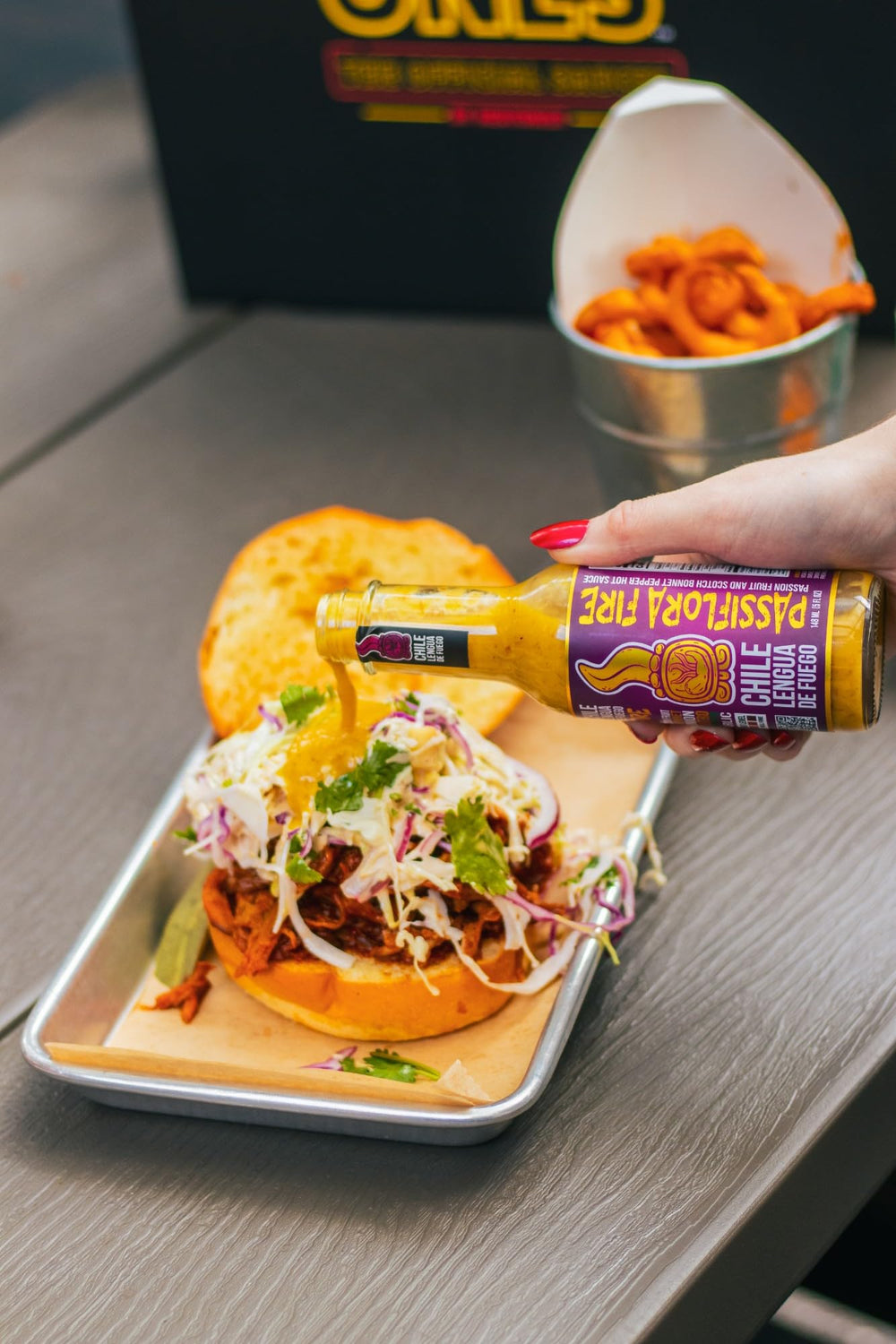 HOT ONES pouring sauce over taco demonstrating versatile serving use