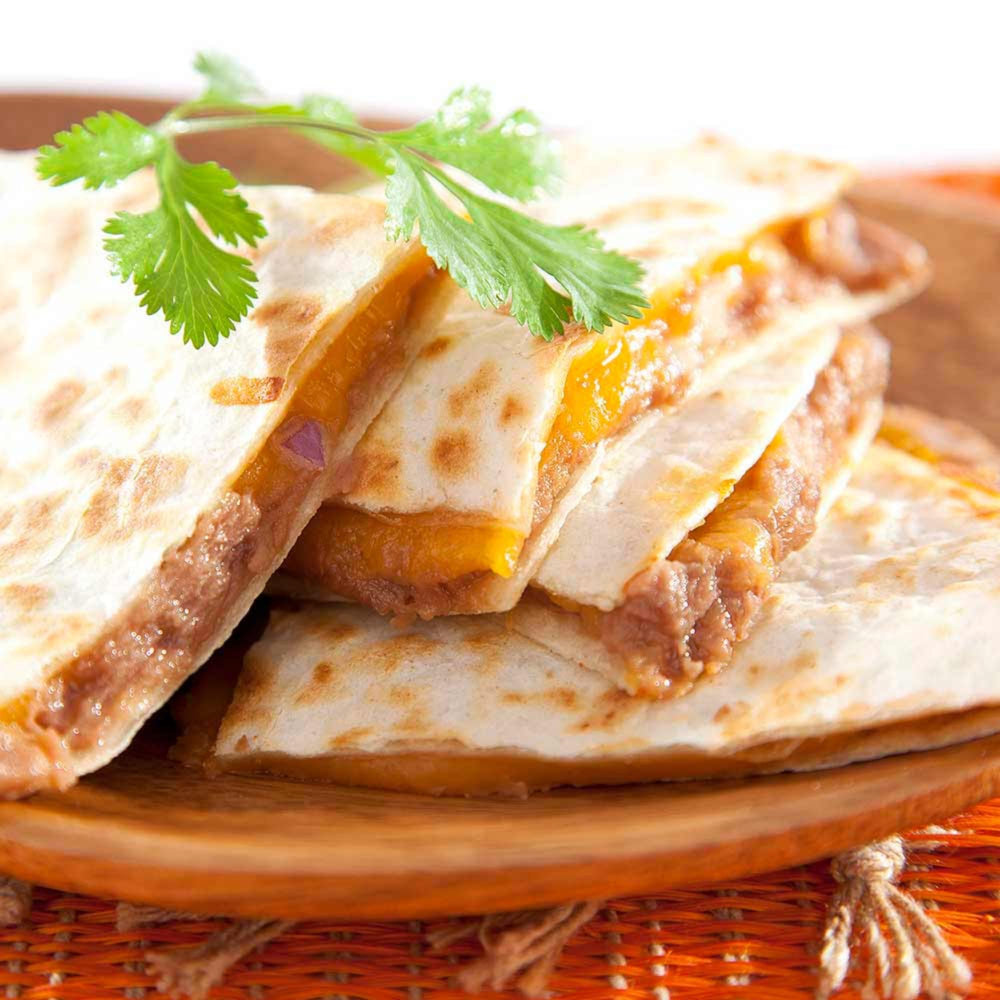 Isadora refried beans spread on a tostada with toppings, fast party-ready dip option