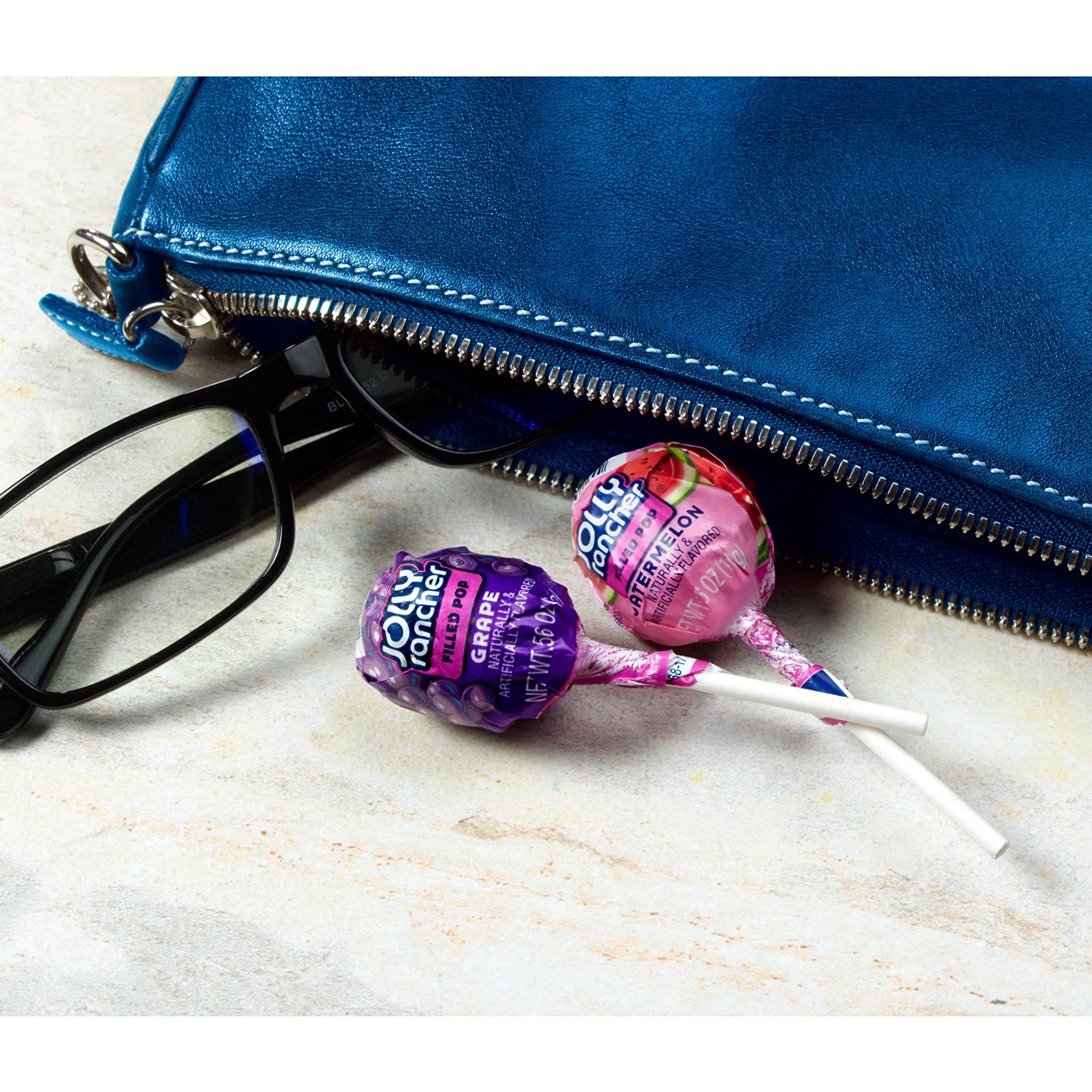 Jolly Rancher pop in hand to illustrate size and grab-and-go convenience