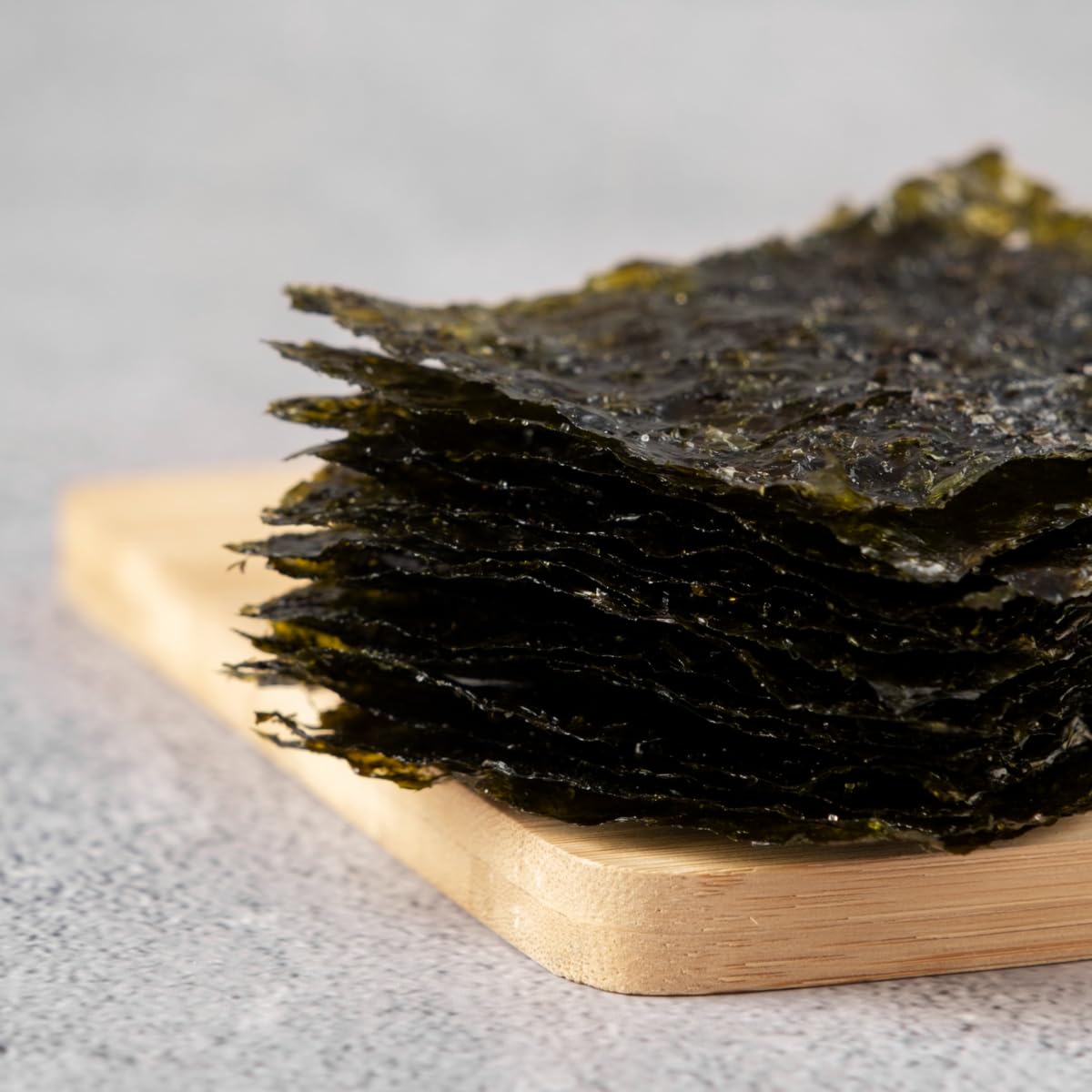 Kimchi Spicy Korean Crispy Seaweed Snacks held in hand shows thin, travel-friendly size