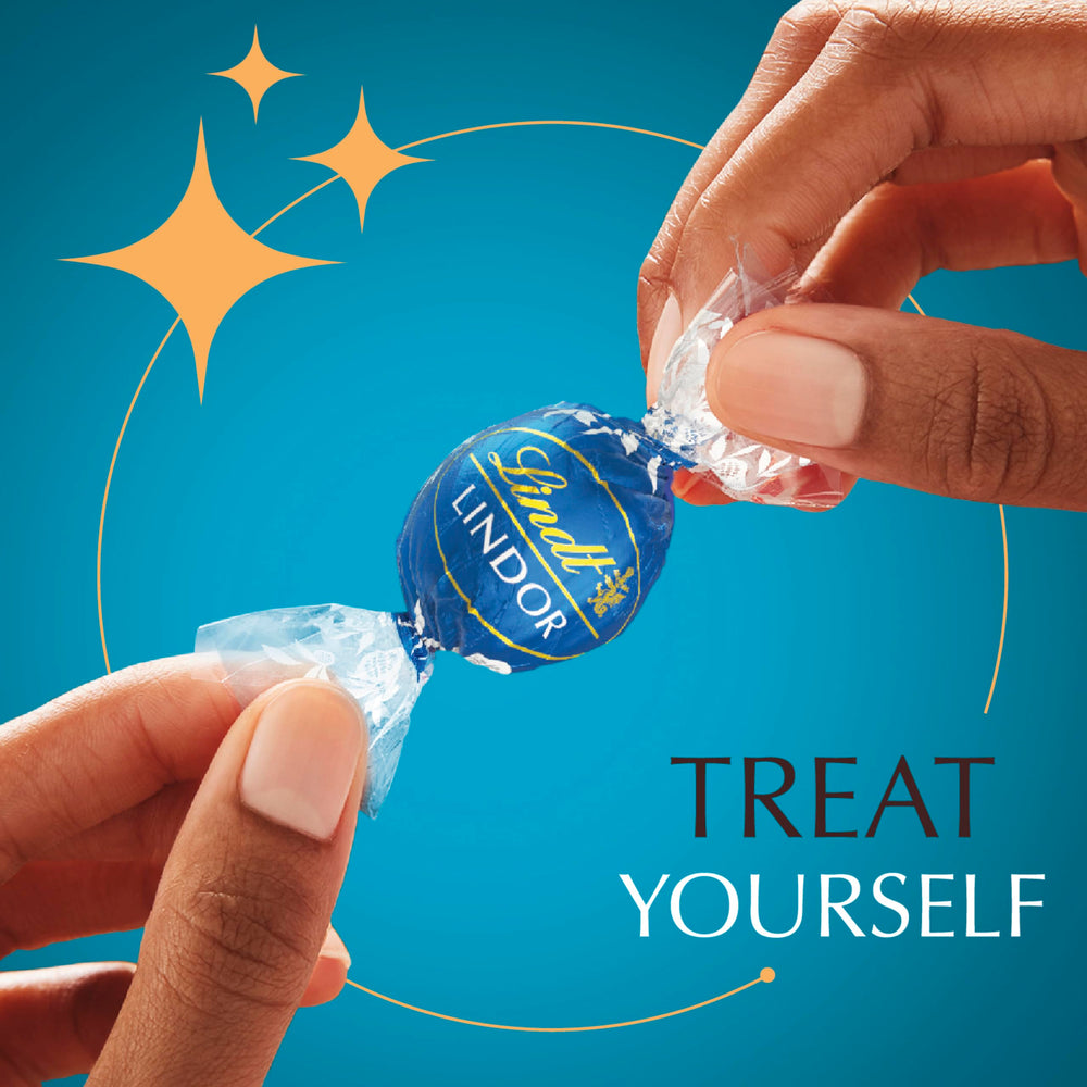Lindt LINDOR truffle in hand for scale illustrating generous portion and gifting suitability