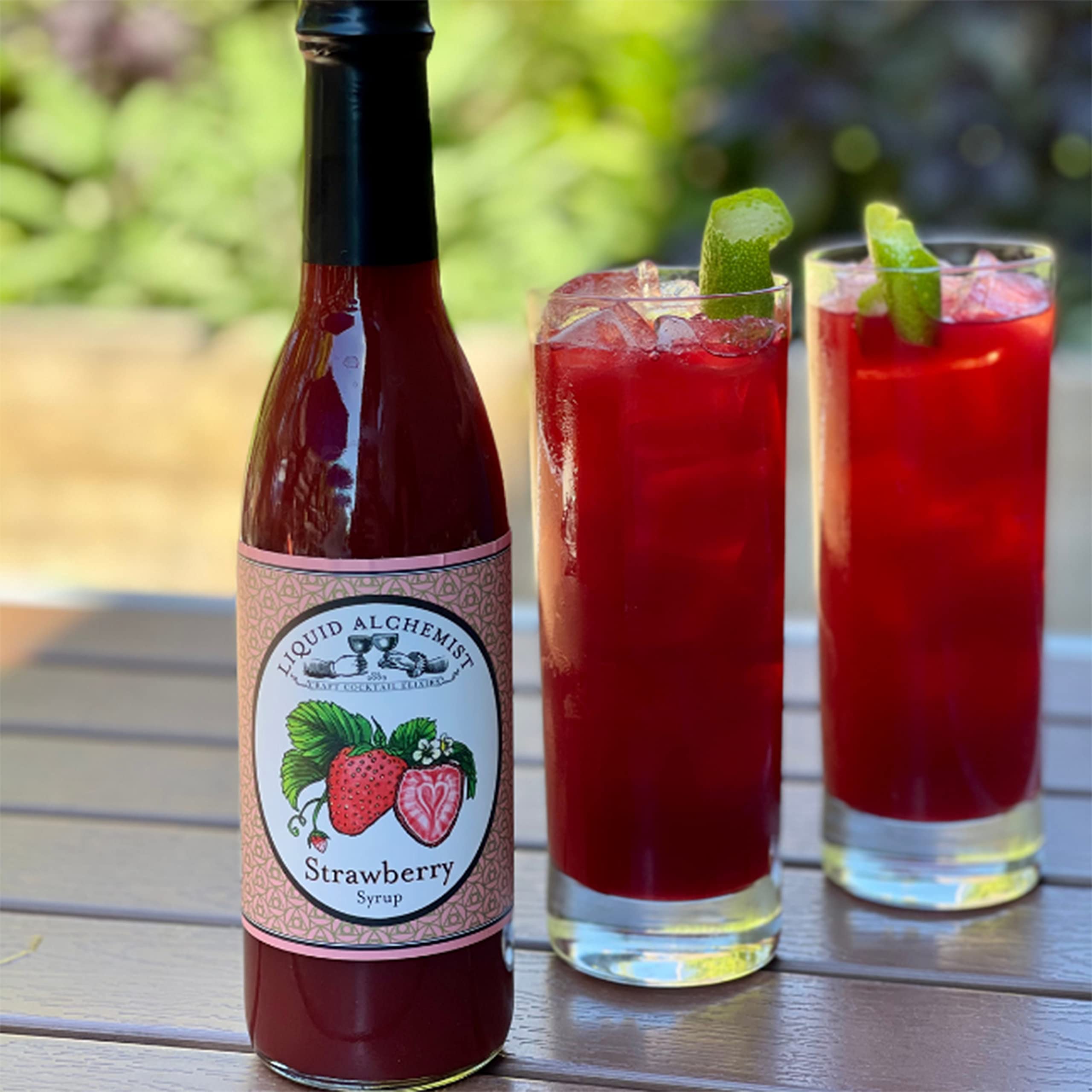 Liquid Alchemist bottle staged with cocktails and garnish showing ready-to-serve benefit