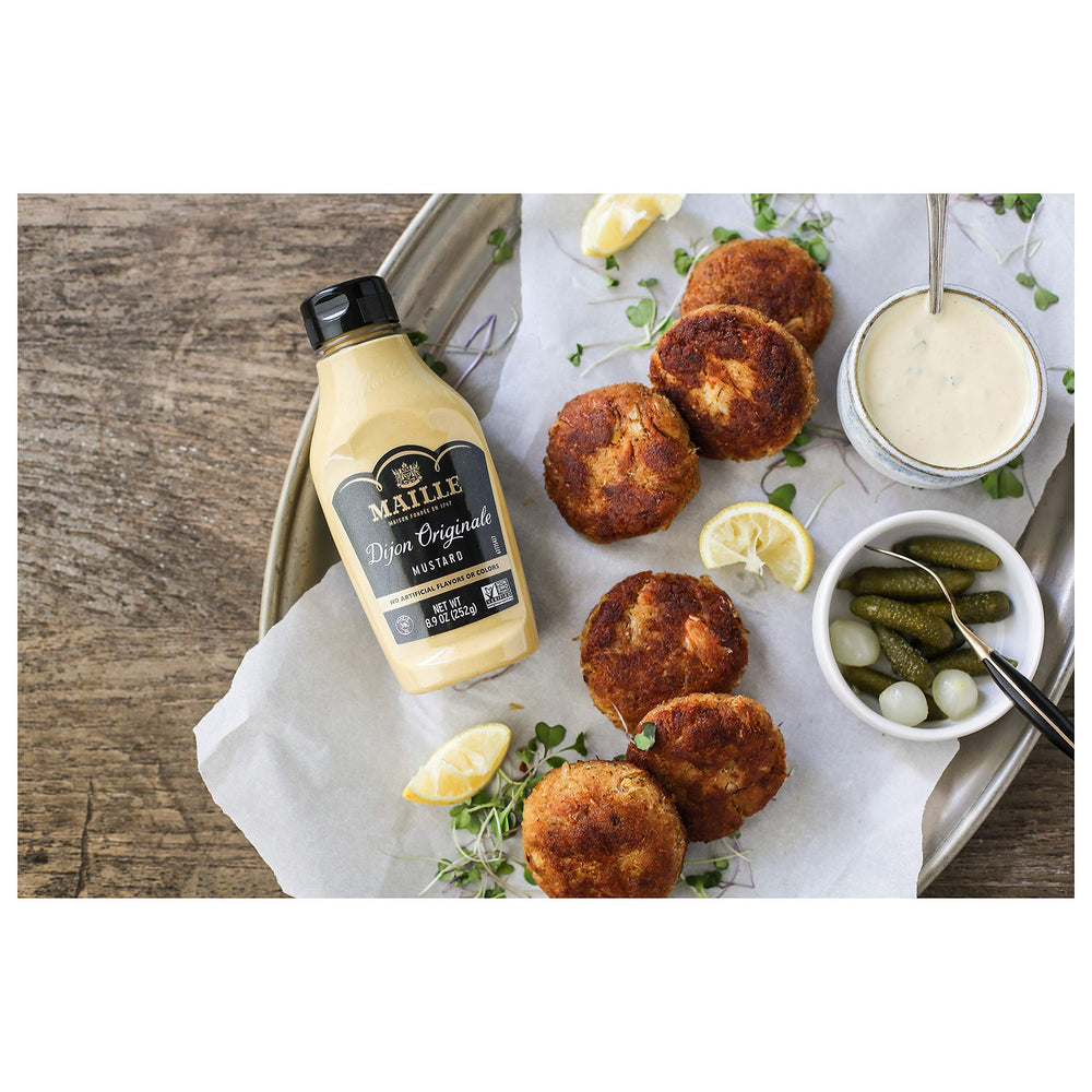 Maille Dijon being spread on a sandwich to add tangy flavor and balance