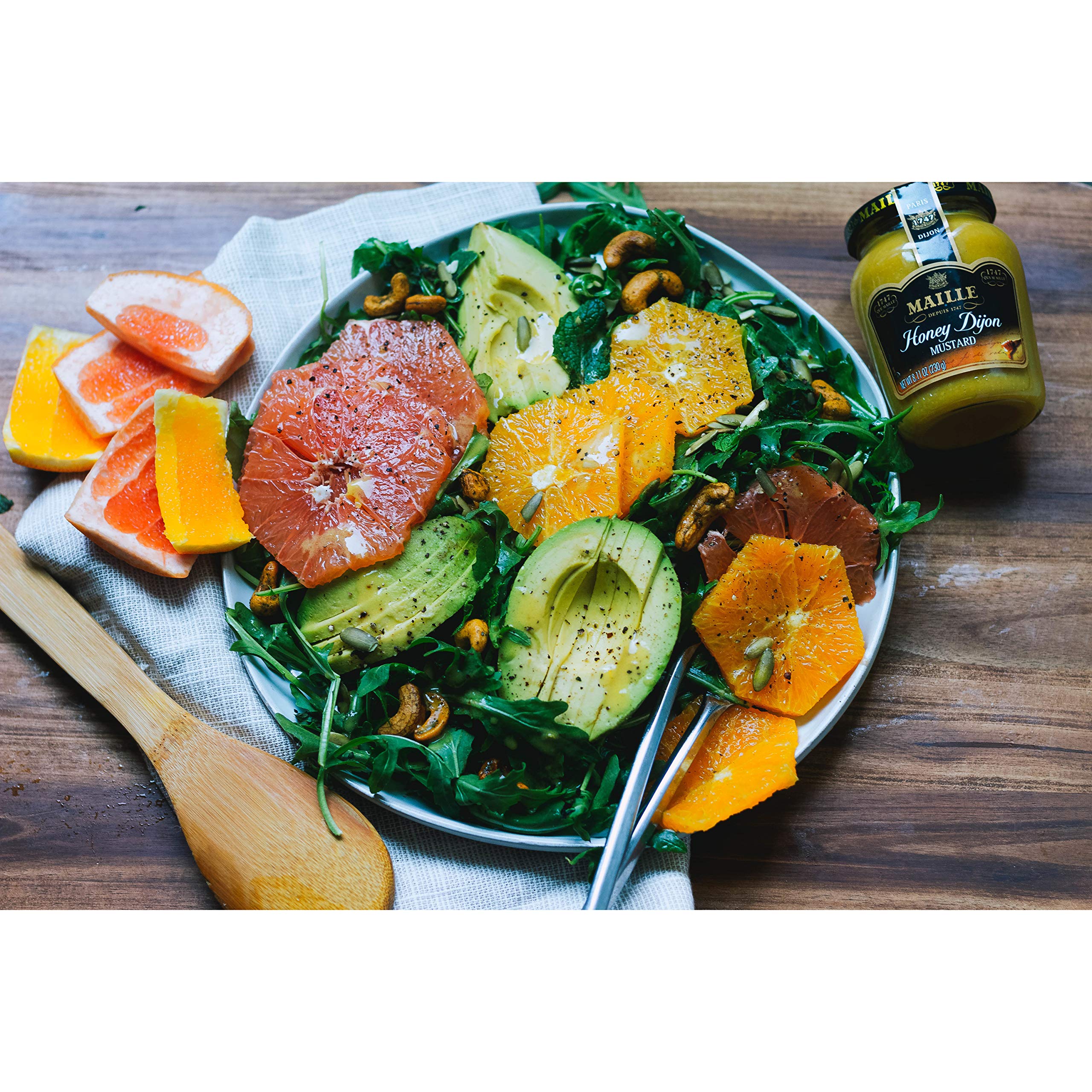 Maille on charcuterie board beside cheeses offering a tangy-sweet accent to pairings