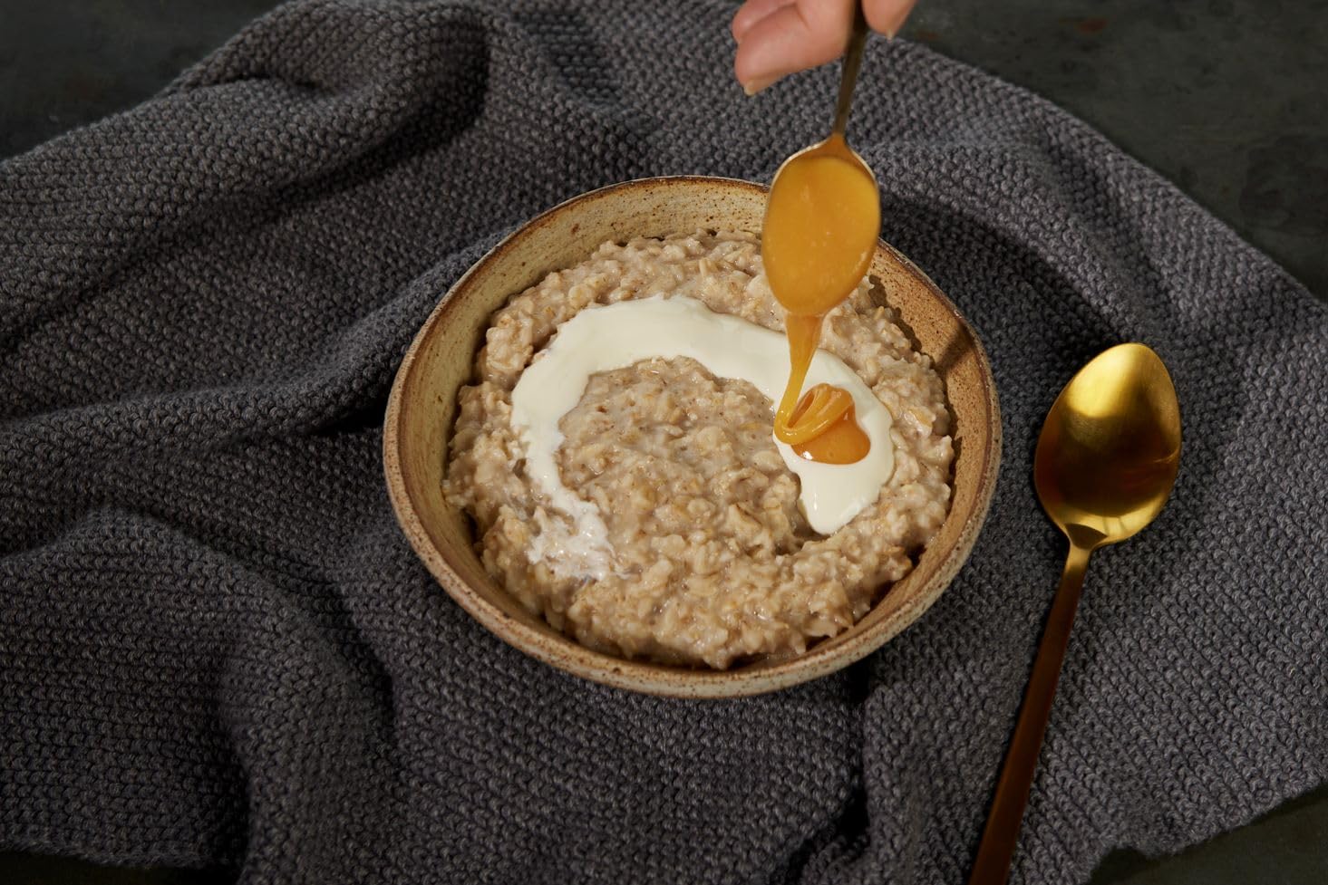 Manuka Health honey dripping from a wooden spoon illustrating creamy texture benefit
