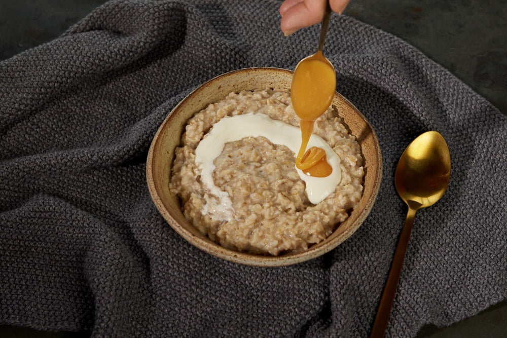 Manuka Health honey dripping from a wooden spoon illustrating creamy texture benefit