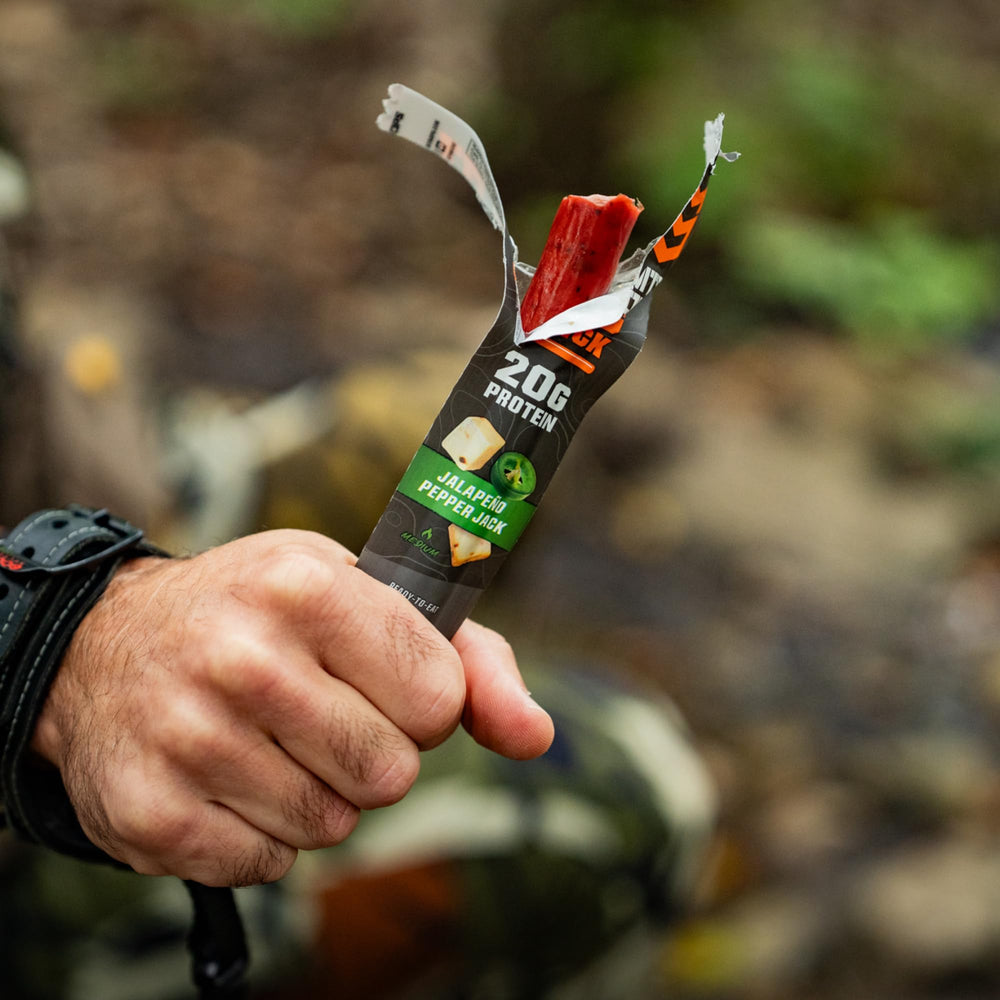 MTN OPS stick inside a backpack pocket illustrating outdoor-ready protein snack