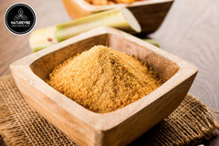 Naturevibe Botanicals wooden spoon holding jaggery powder illustrating easy measuring and scooping