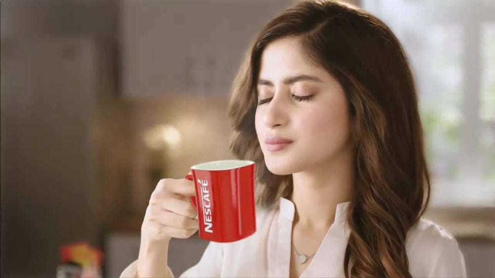 Nescafé pouring hot water into mug with sachet creating instant froth and flavour