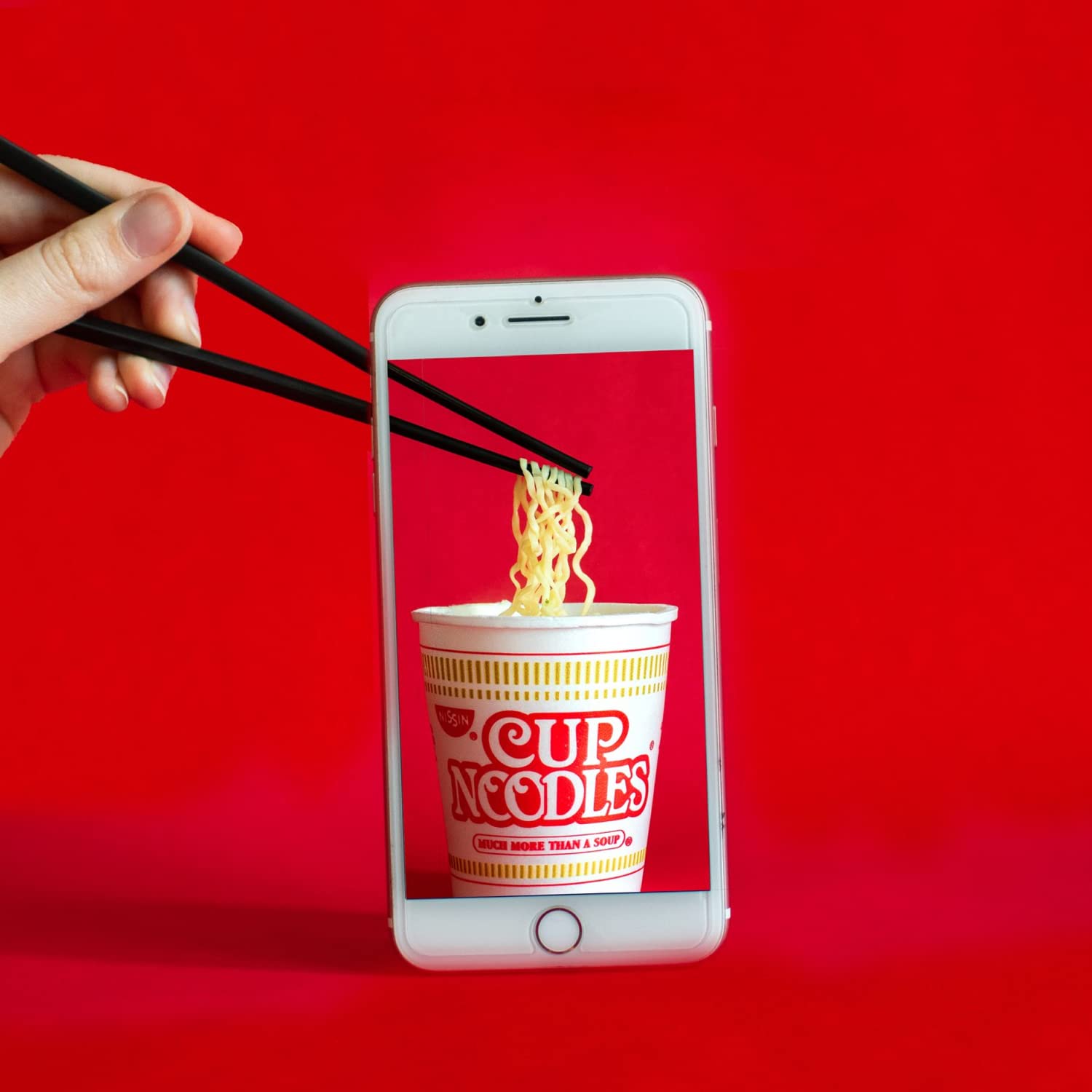 NISSIN cup next to hand for size comparison showing portable single-serve convenience