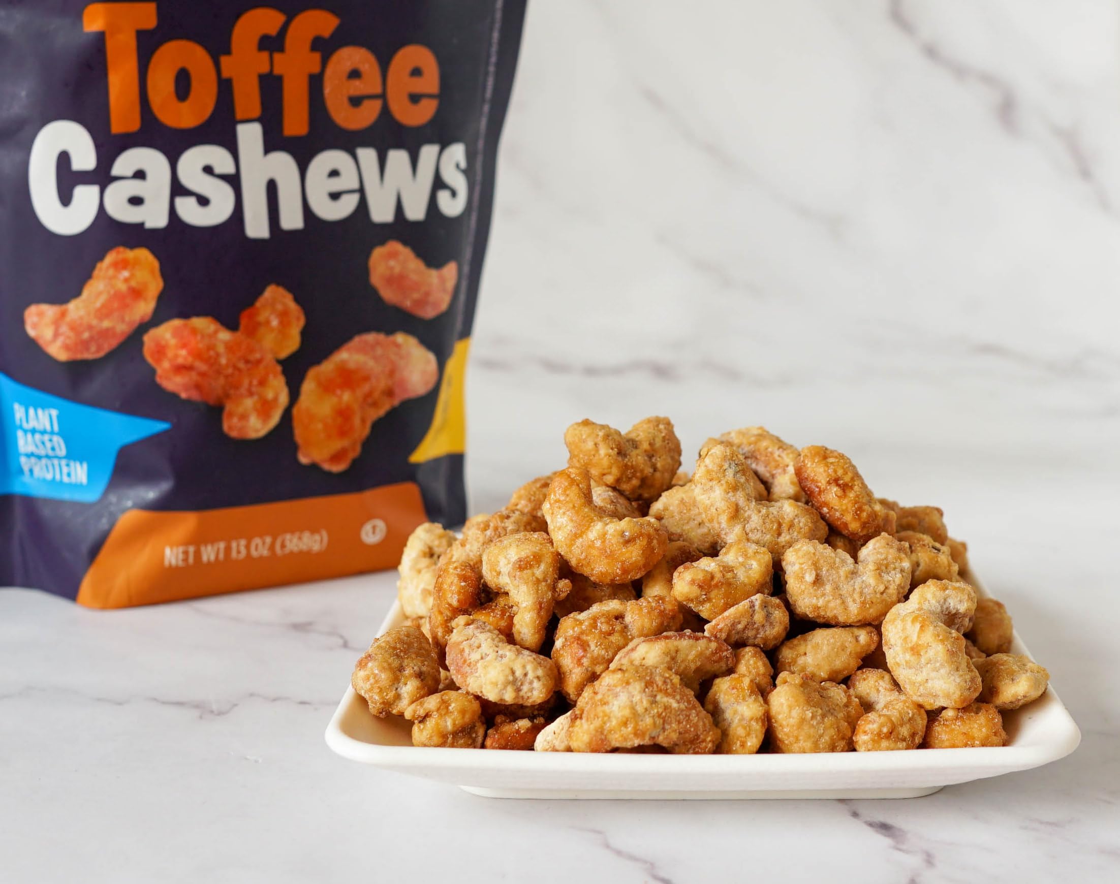 Platinum cashews in hand for scale illustrating 13 oz pouch portability and snackable size