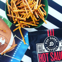 Pop Daddy open bag with pretzels pouring onto a wooden table showing resealable convenience and portability