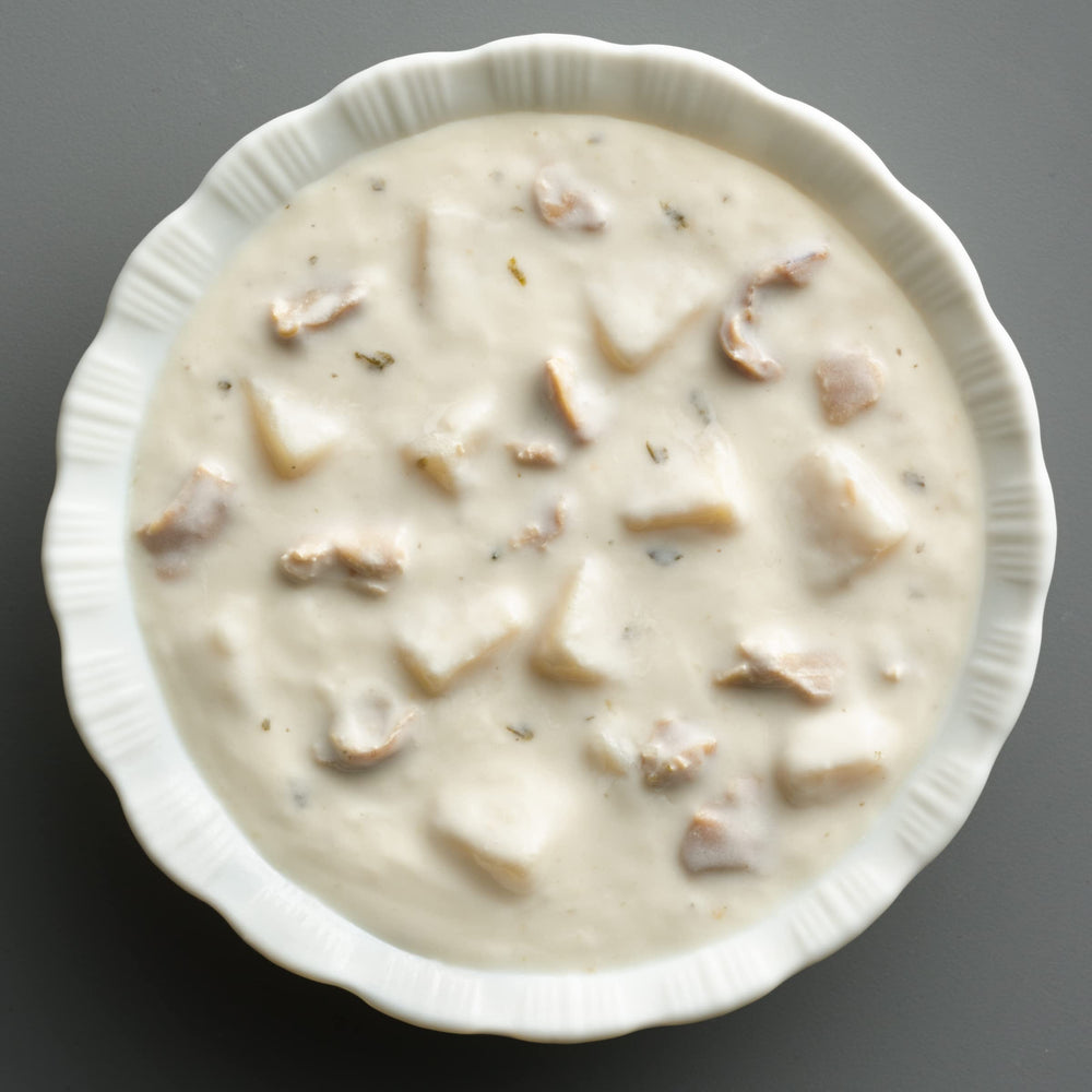 Bowl of Progresso chowder next to crusty bread demonstrating serving idea