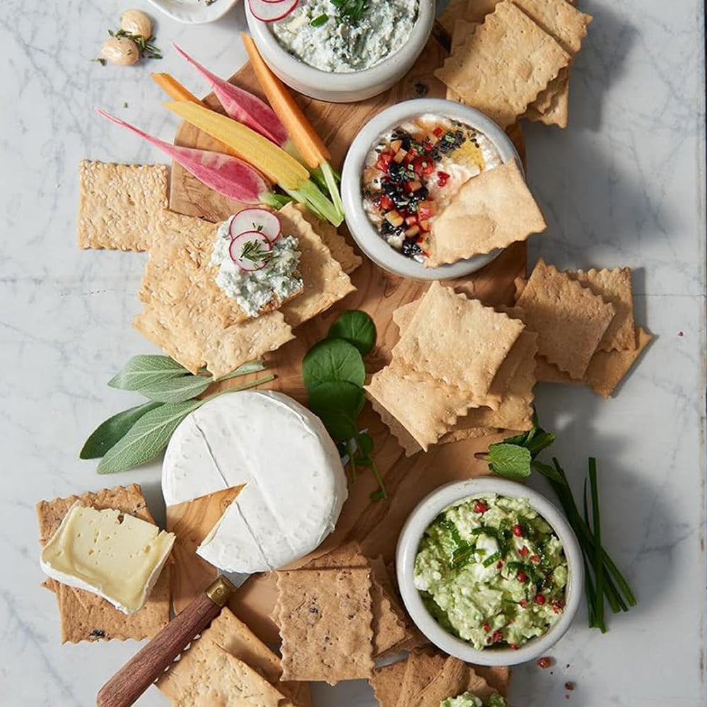 Rustic Bakery crackers dipped into hummus in a casual setting, showing easy serving idea