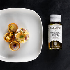 Sabatino Tartufi drizzling oil over pasta to add white truffle aroma and savory depth
