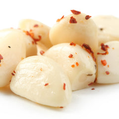 Sanniti pickled garlic on a charcuterie board adding tangy contrast to cheeses