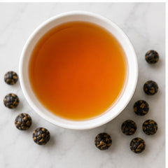 Tealyra pearls steeping in a glass cup releasing amber liquor and delivering smooth flavor