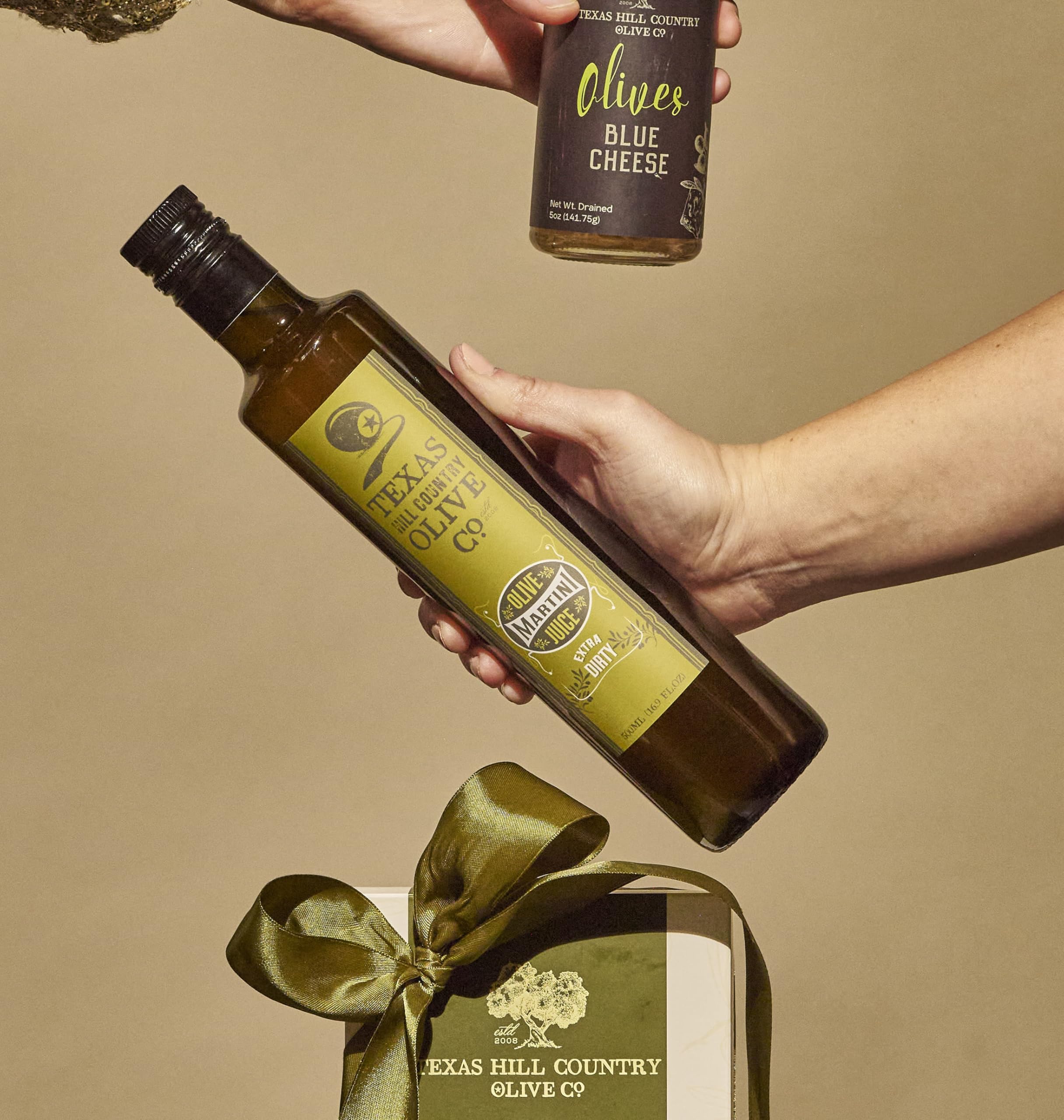 Pouring Texas Hill Country Olive Co. olive juice into a martini glass for bold flavor