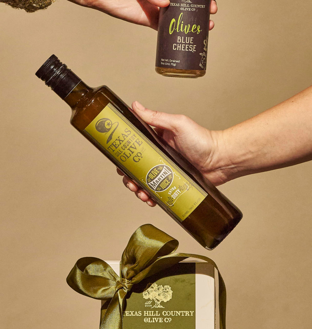 Pouring Texas Hill Country Olive Co. olive juice into a martini glass for bold flavor
