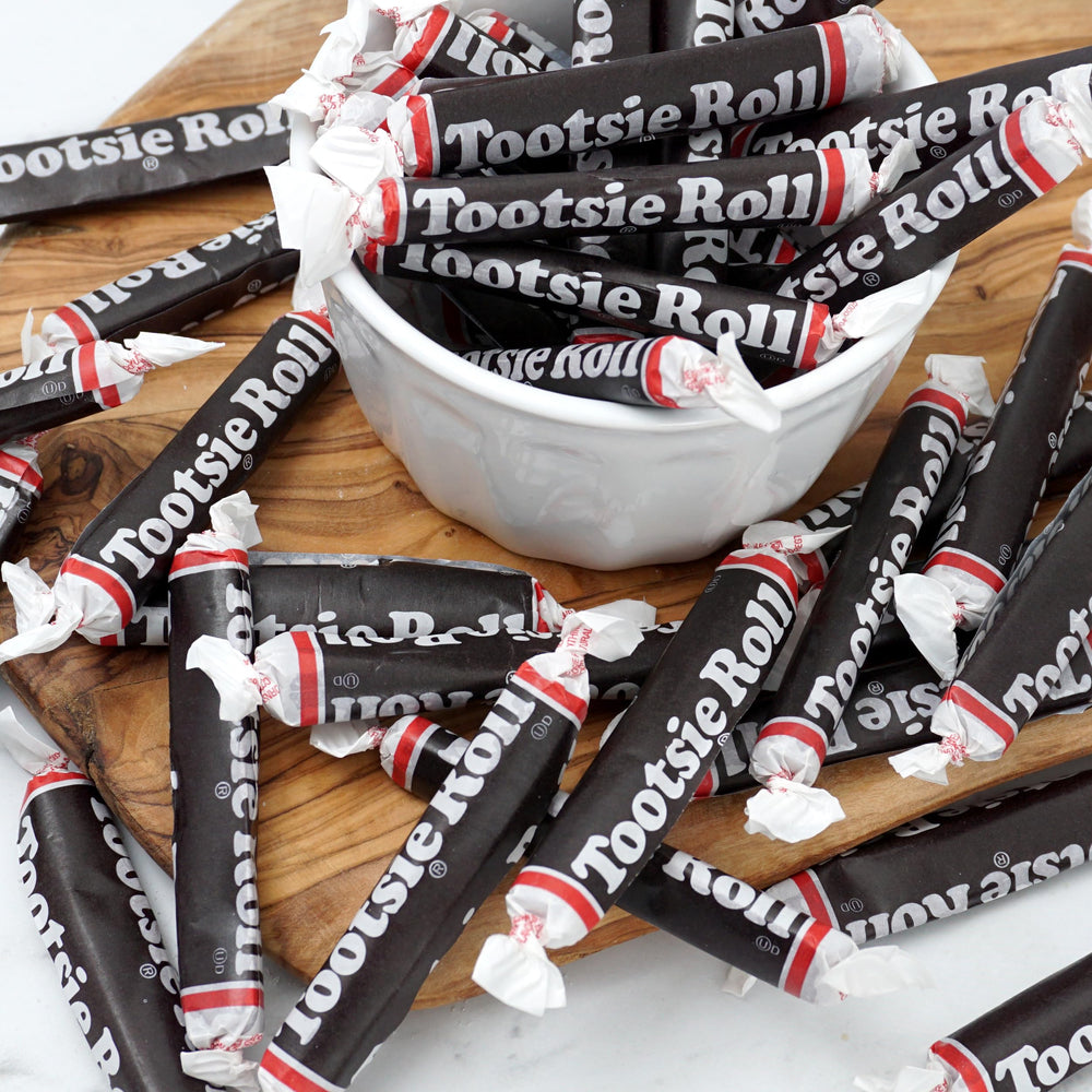 THE HAMPTON CANDY COMPANY hand holding a 3-inch Tootsie Roll to show size and portion